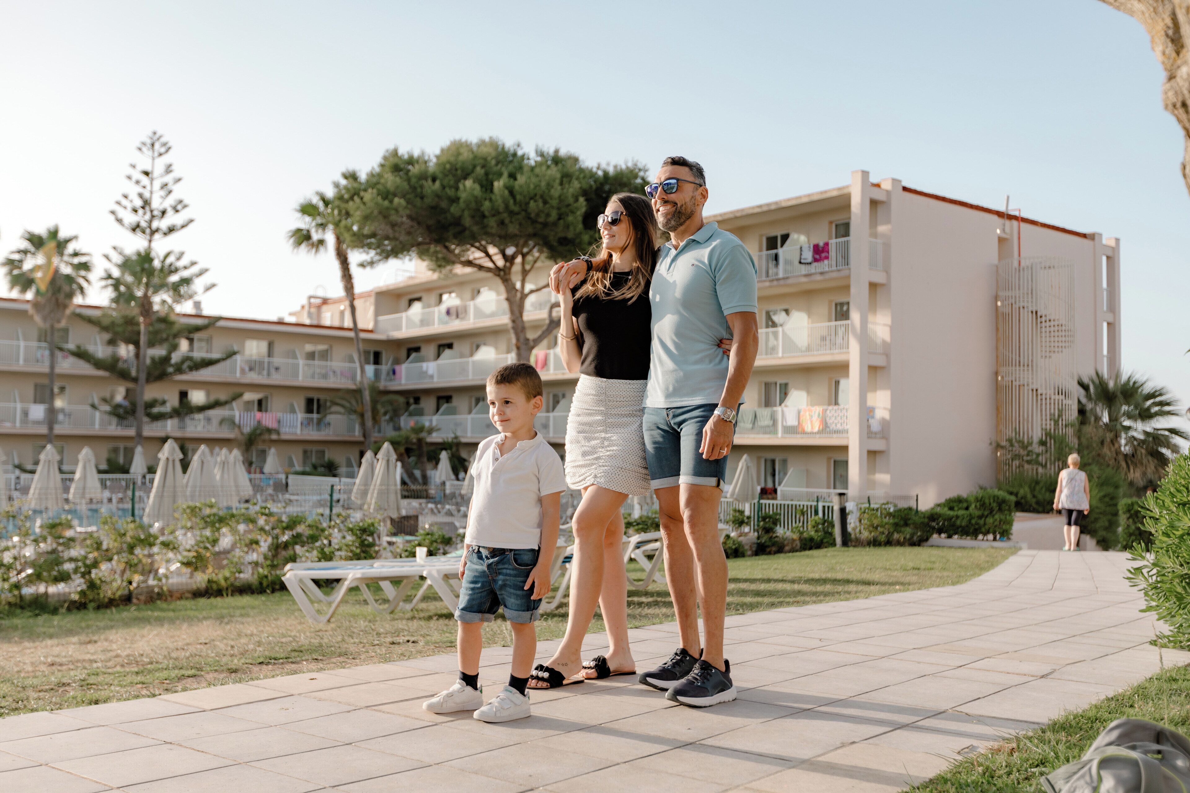 A family standing on a paved pathway with a building in the background.