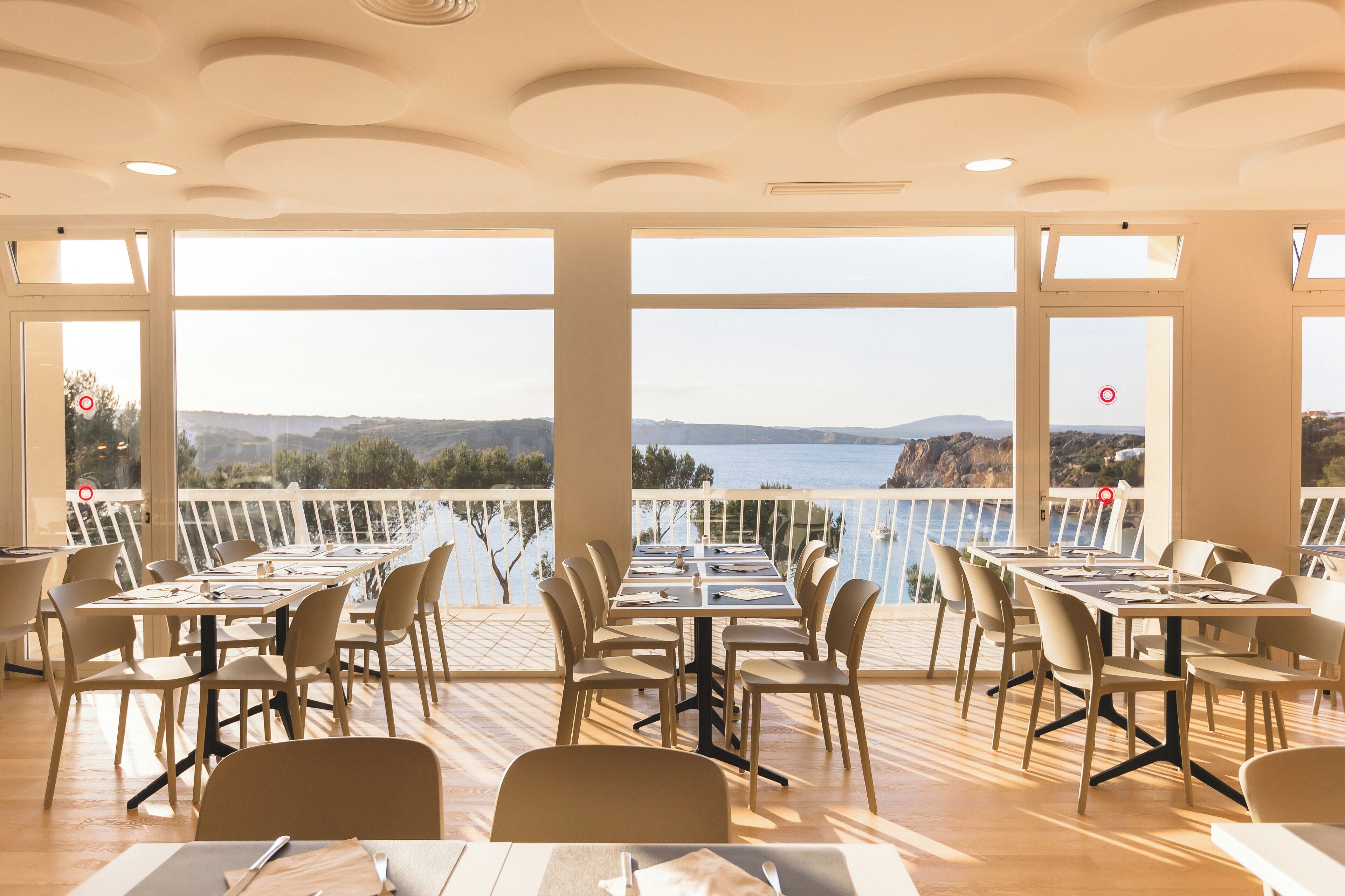 Un restaurante con terraza y vistas panorámicas de un lago y montañas.