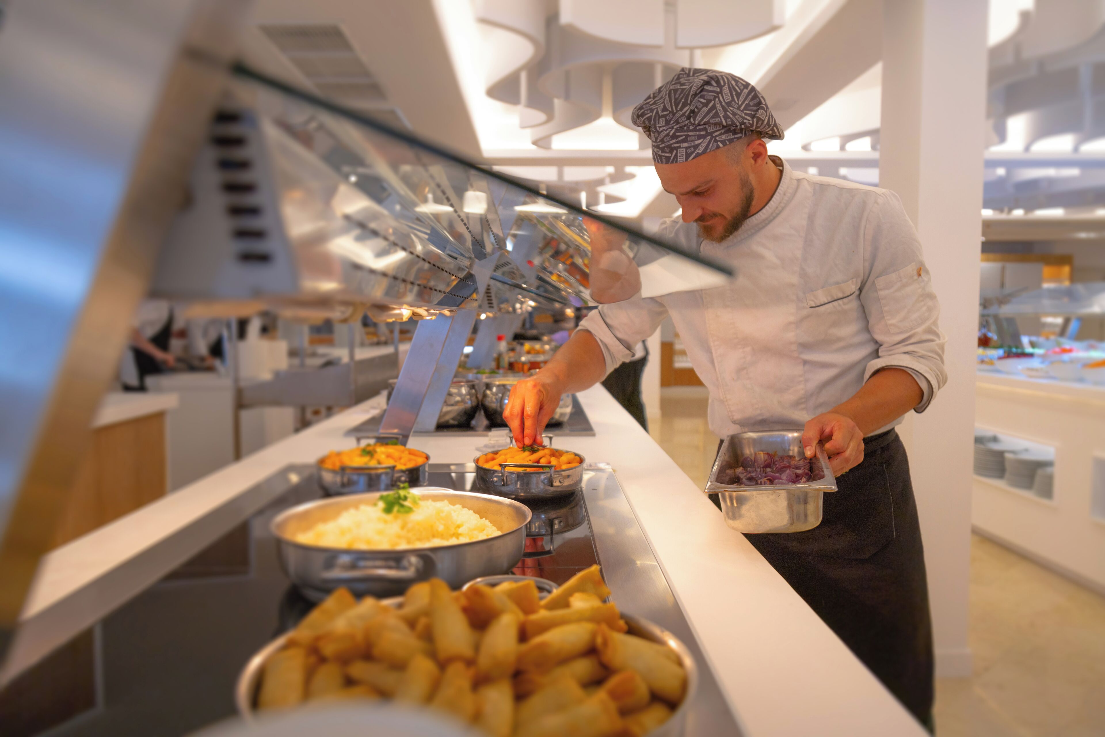 Zona de bufé con diversas opciones de comida y una persona atendiendo.