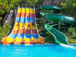 Un tobogán acuático de varios niveles con secciones de colores y una piscina al final.