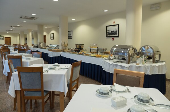A dining area with multiple tables set for breakfast, each with a variety of food items and utensils.