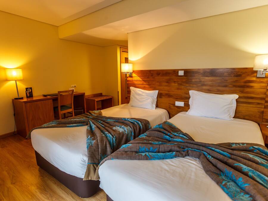 A hotel room with two beds, a desk, and a chair.