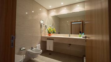A modern bathroom with a bidet, toilet, sink, and a large mirror.