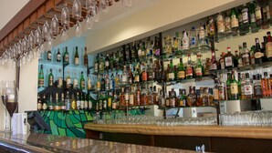 A bar area with multiple shelves of liquor bottles and a variety of glasses. - Hotel Caravelas (Madalena)