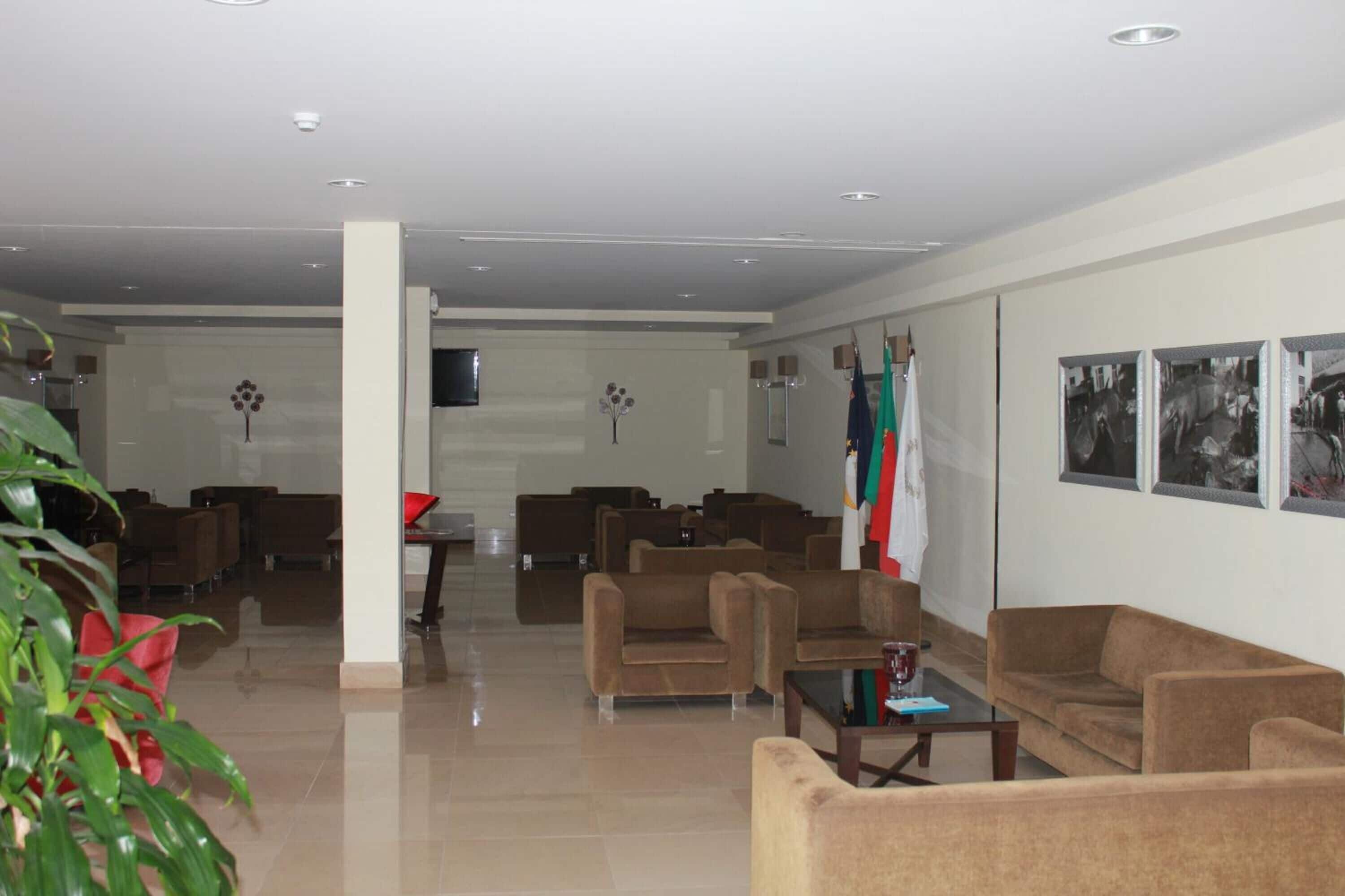 A spacious lobby with multiple seating areas, a television mounted on the wall, and flags on the right side.