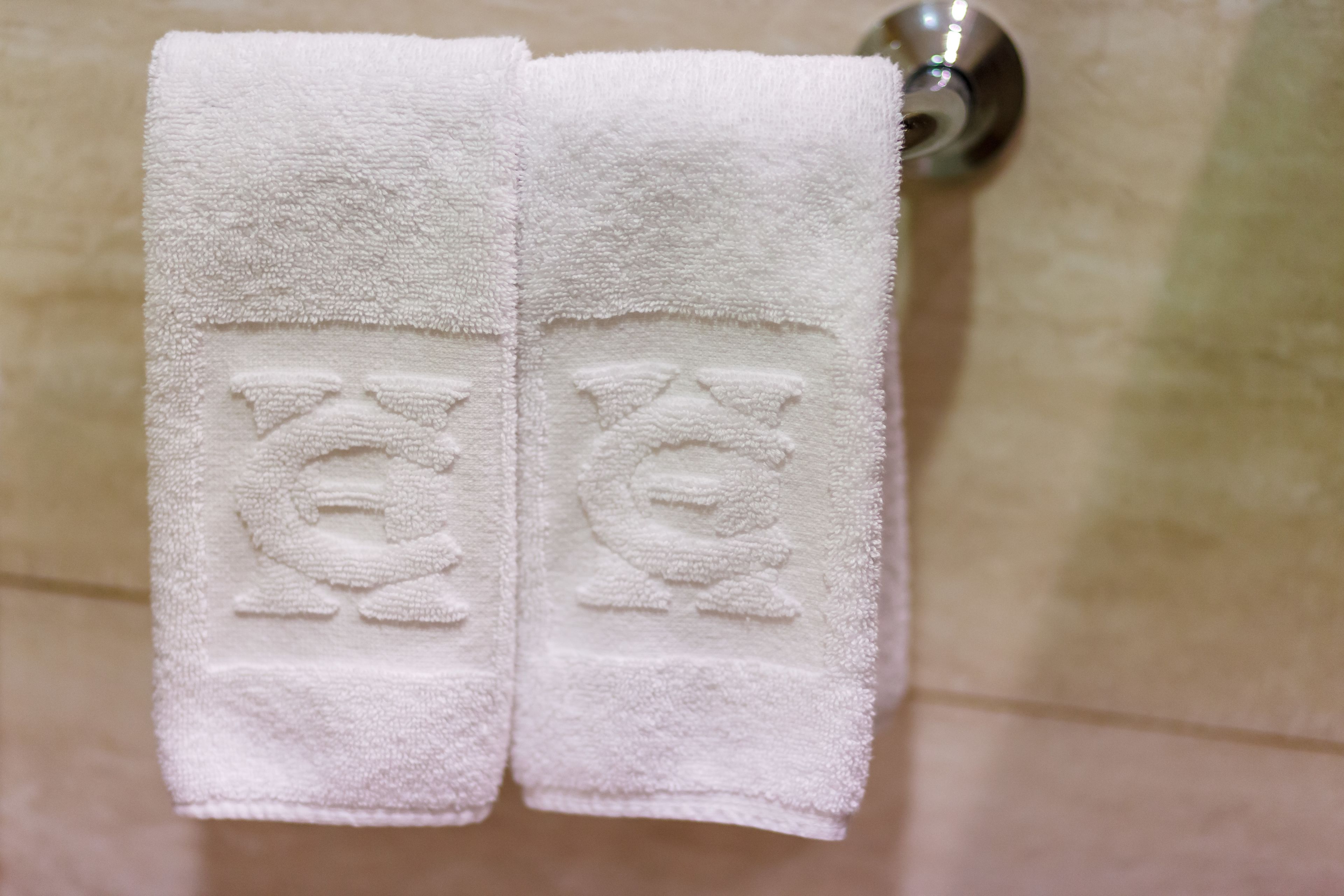 A white towel with embossed designs hanging on a bathroom wall.
