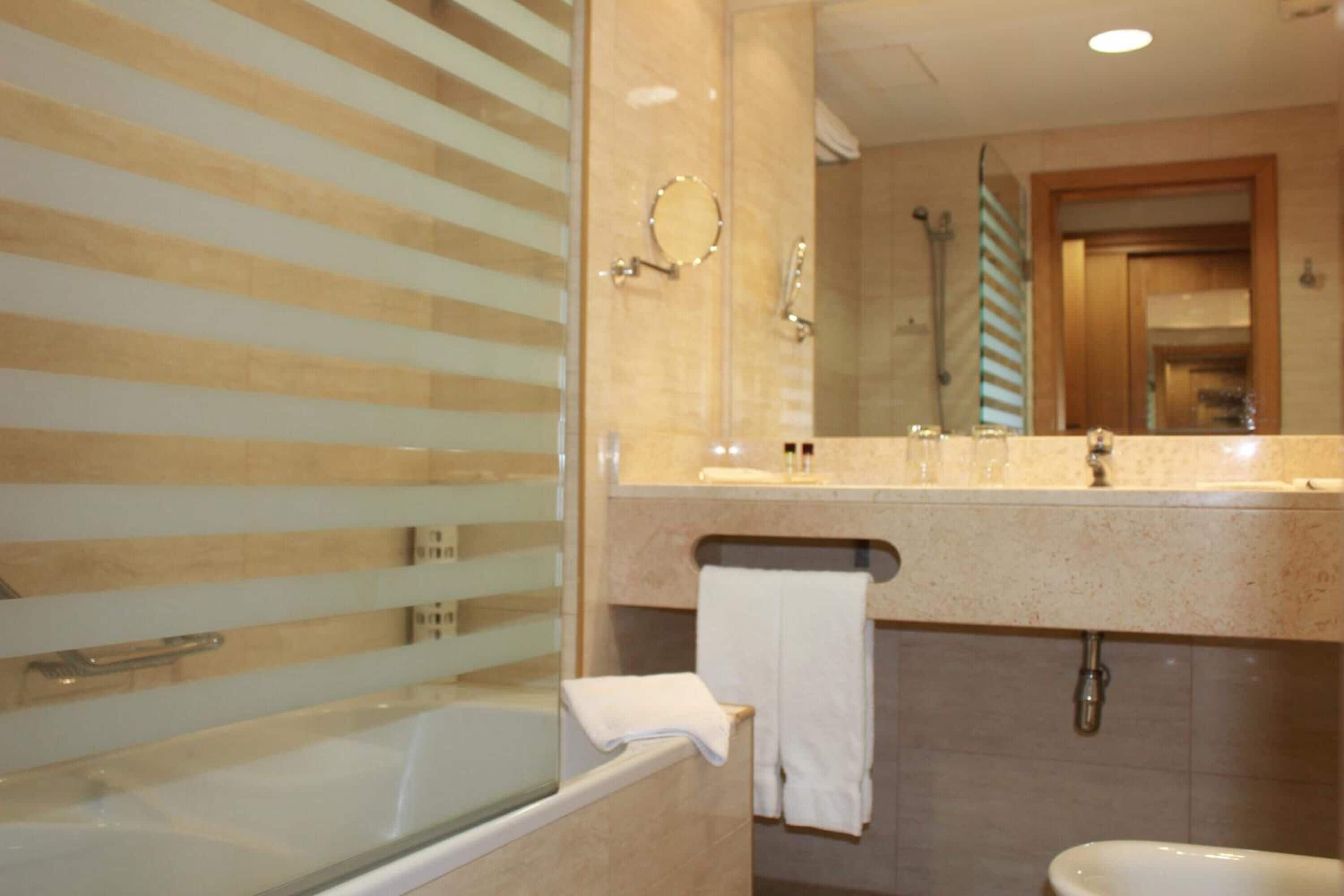 A modern bathroom with a glass-enclosed bathtub, a vanity with a mirror, and a shower area.