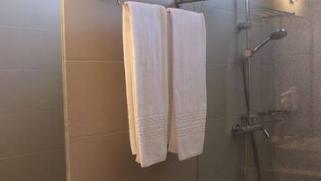 A bathroom with a sink, mirror, towel rack, toilet, and shower.