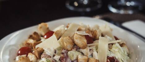 A plate of salad with croutons, cheese, and cherry tomatoes.