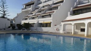 Una piscina junto a un edificio moderno de varios pisos con balcones.