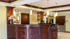 A reception area with a wooden reception desk, framed certificates, and a sign for 'Comfort Suites'.