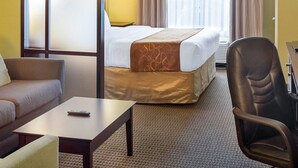 A hotel room with a bed, a sofa, a chair, a table, and a window with curtains.