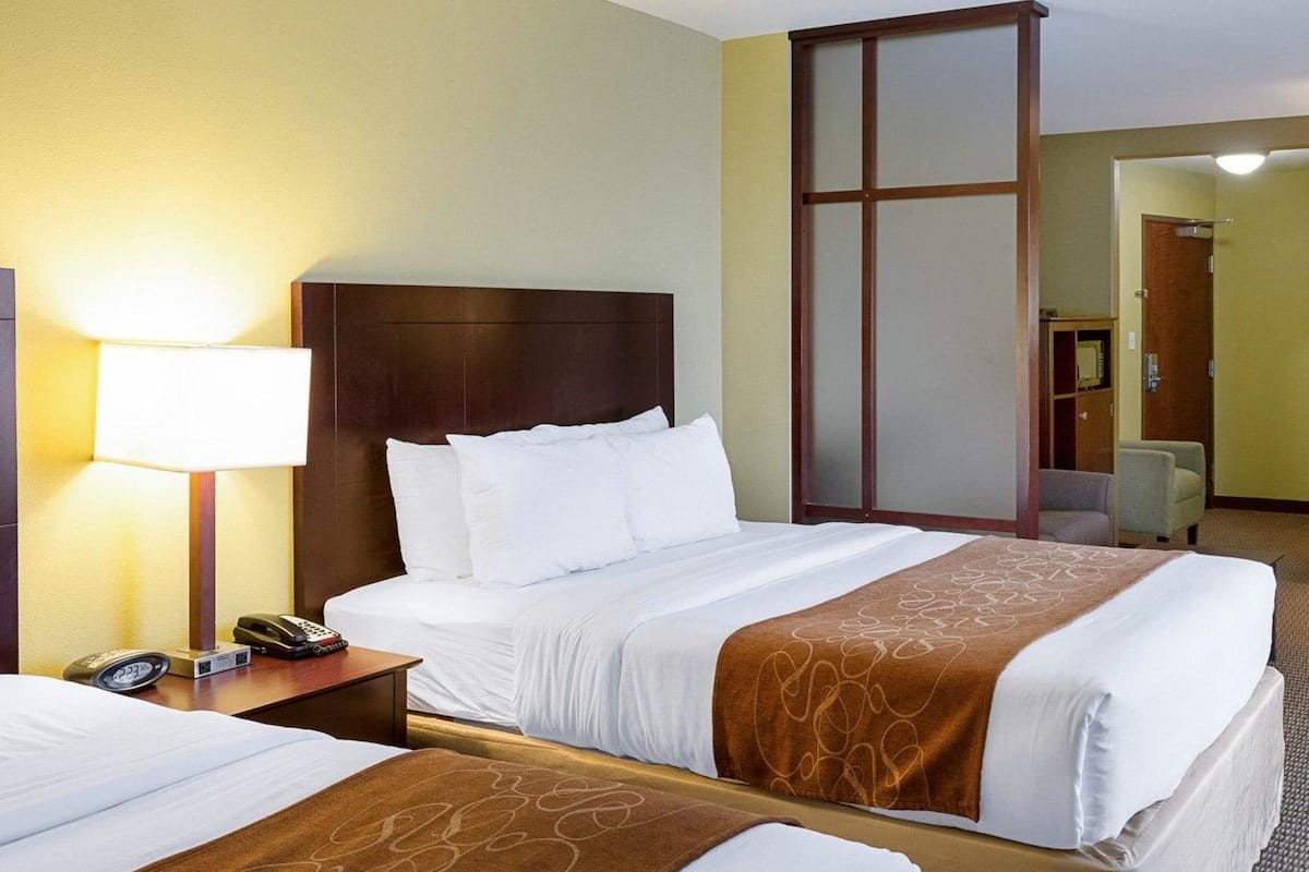 Een hotelkamer met een groot bed, een nachtkastje met een lamp, een telefoon en een stoel.