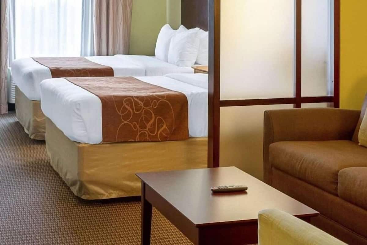 Een hotelkamer met twee bedden, een bank, een salontafel en een televisie.