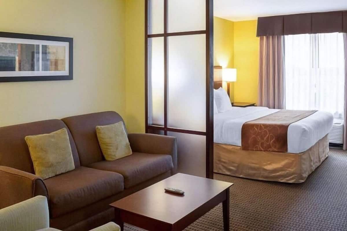Een hotelkamer met een sofa, een bed, een bijzettafeltje en een raam met gordijnen.