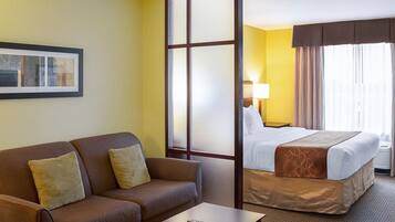 Habitación de hotel con sofá, cama, mesita de centro y mesita de noche.