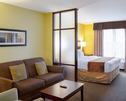 Habitación de hotel con sofá, cama, mesita de centro y mesita de noche.