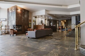 A spacious lobby with a stone floor, a reception desk, and a staircase with golden railings. - Quality Inn Rouyn - Noranda (Rouyn-Noranda)