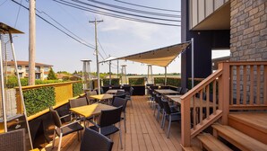 Un patio al aire libre con mesas y sillas, una terraza de madera y un muro de ladrillo.
