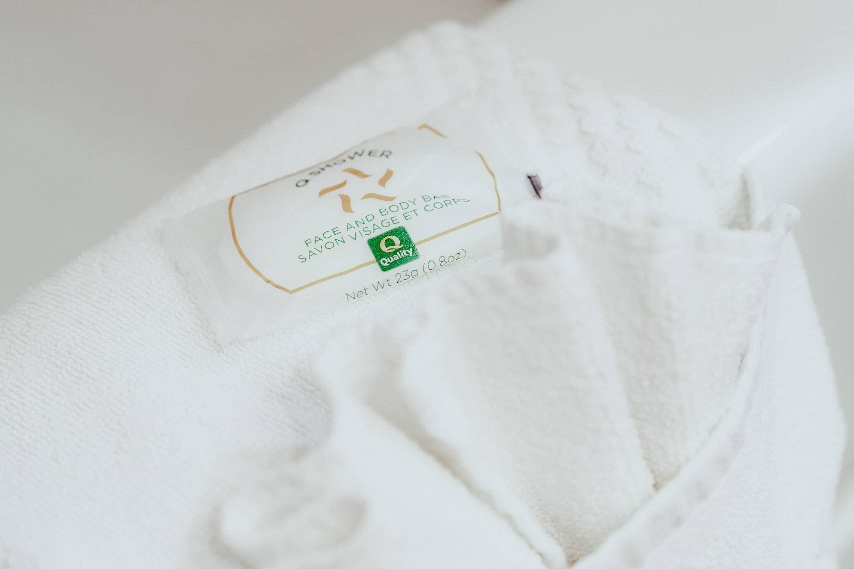 A white towel with a label indicating it is a quality product for face and body use.