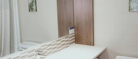 A bathroom with a white sink, a mirror, a toilet, and a shower curtain.