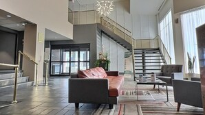 Un hall amplio con diseño moderno, que incluye un sofá de cuero, una escalera y un candelabro.