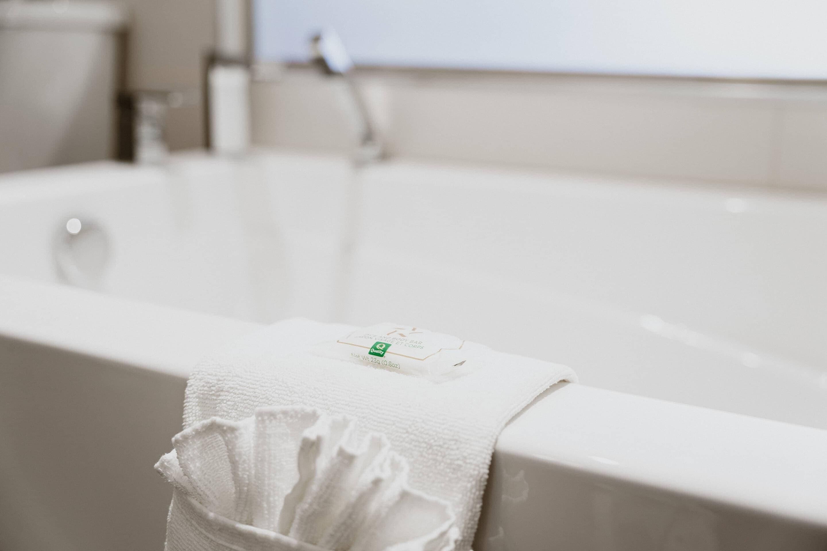 A white bathtub with a towel draped over the edge.