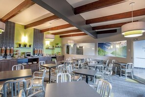 A modern restaurant with exposed wooden beams, a bar area, and large windows offering a view of the outdoors.