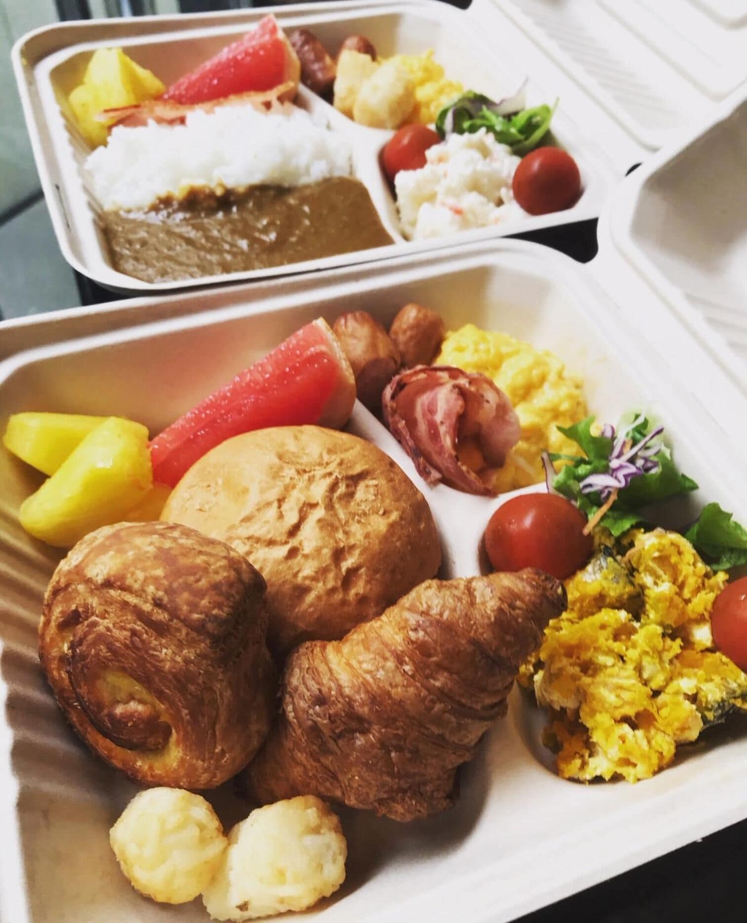 A meal with various dishes including a baked chicken leg, sausages, and a salad.