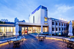 Ein modernes Hotel mit Dachterrasse, Sitzgelegenheiten im Freien und einem Pool.