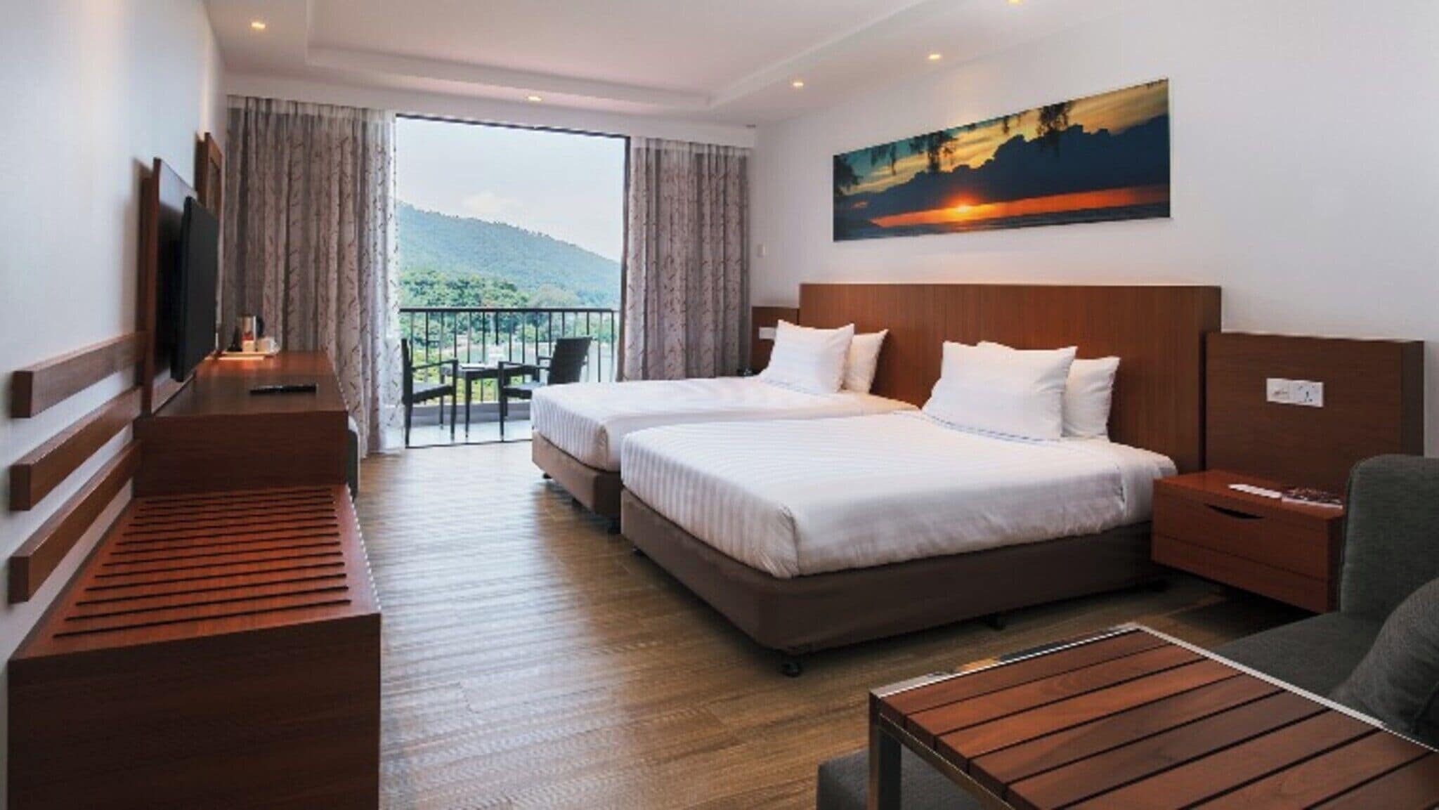 A hotel room with two beds, a desk, a TV, and a balcony with a view of the mountains.