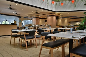 A spacious restaurant with multiple tables and chairs, ceiling fans, and a modern interior design. - Bayview Beach Resort Penang (George Town)
