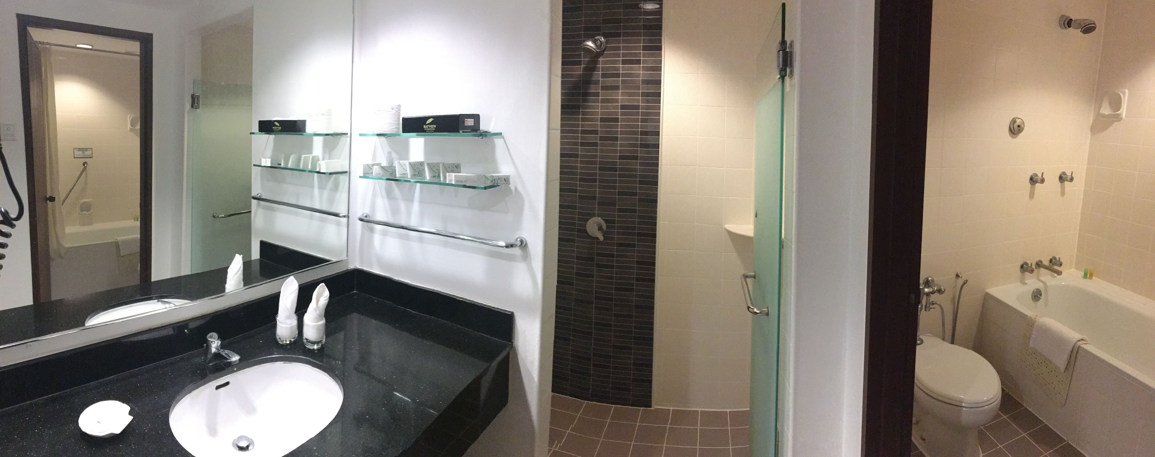 Ein Badezimmer mit schwarzem Waschtisch, weißem Waschbecken und einer Duschkabine aus Glas.