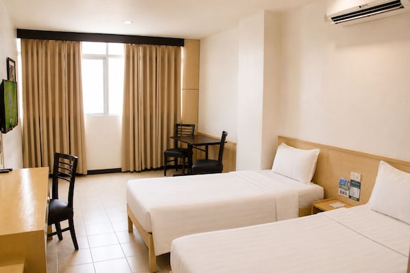 Habitación de hotel con dos camas, un escritorio, una silla y un televisor.