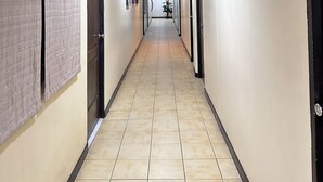 A long, narrow hallway with beige walls and tiled flooring, leading to a door at the end. - Hotel Pier Cuatro (Cebu City)