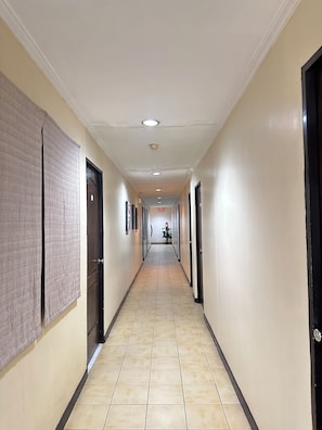 A long, narrow hallway with beige walls and tiled flooring, leading to a door at the end. - Hotel Pier Cuatro (Cebu City)