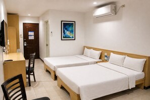 Habitación de hotel con dos camas individuales, un escritorio con una silla, un cuadro en la pared y un equipo de aire acondicionado.
