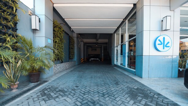 A paved walkway leading to a building entrance with a blue and white facade, potted plants, and a sign indicating a no parking zone. - Hotel Pier Cuatro (Cebu City)