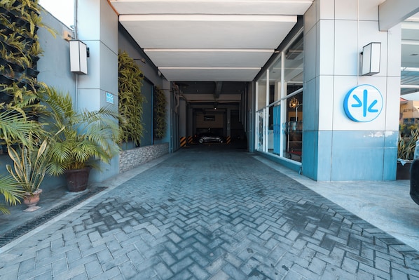 A paved walkway leading to a building entrance with a blue and white facade, potted plants, and a sign indicating a no parking zone. - Hotel Pier Cuatro (Cebu City)