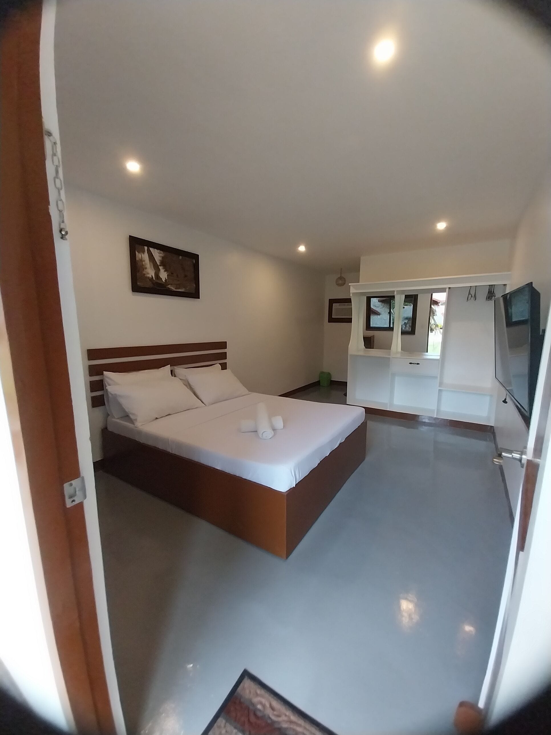 A modern bedroom with a large bed, a small desk, and a television.