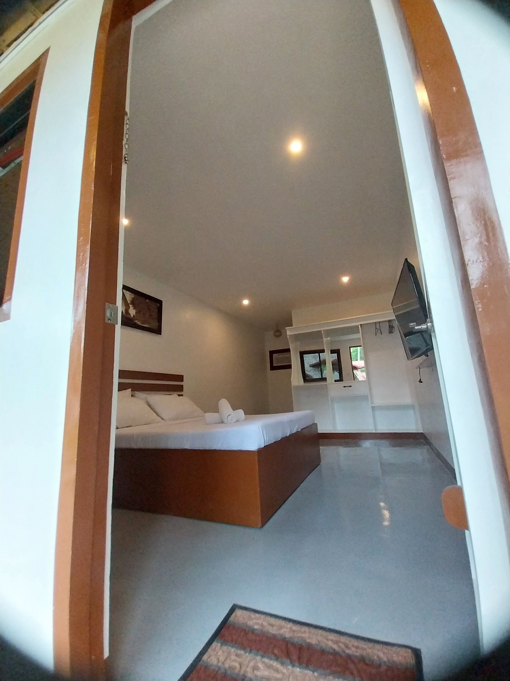 A bedroom with a bed, a small desk, and a television.