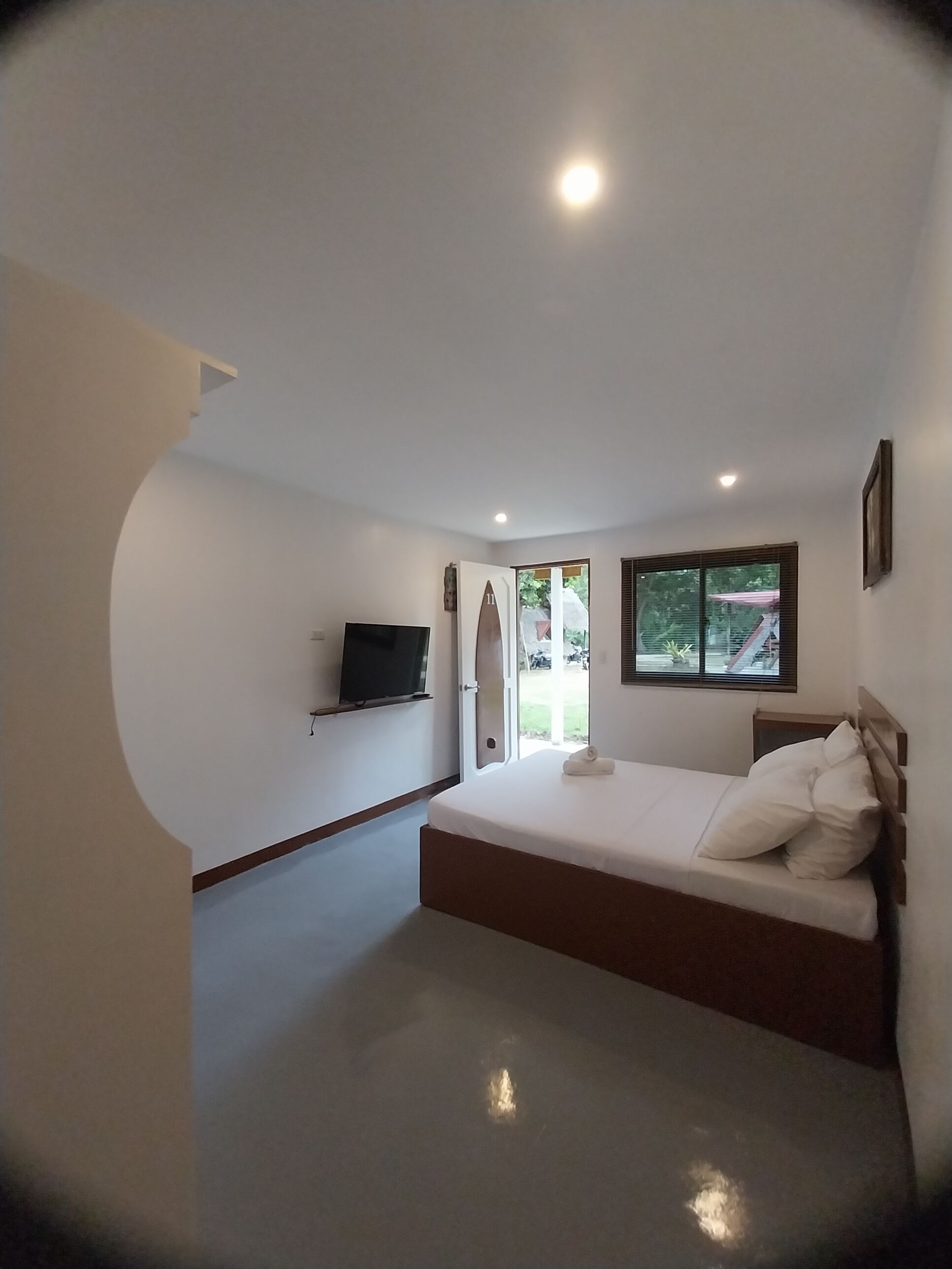 A bedroom with a bed, a TV, and a window.