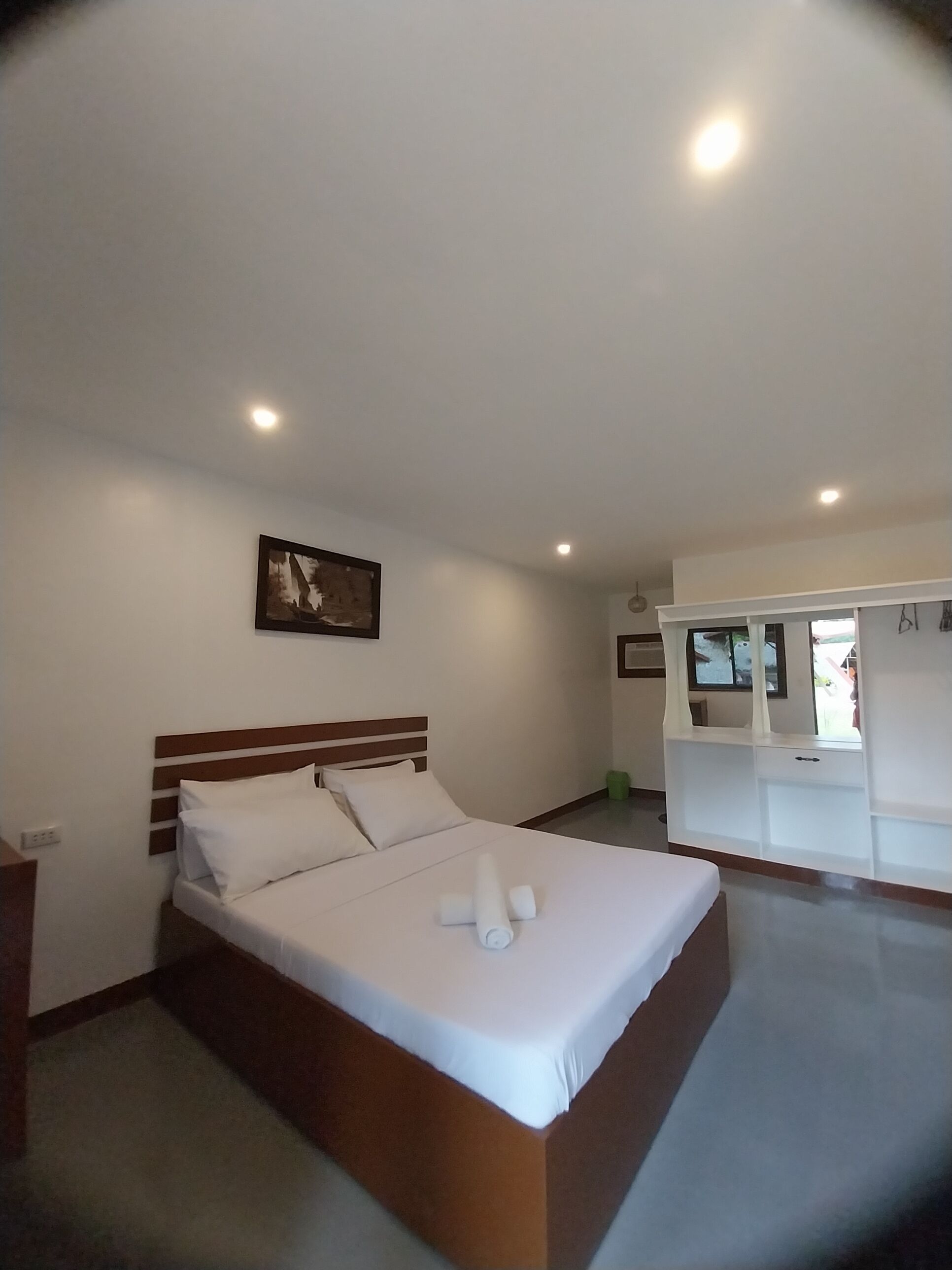 A bedroom with a bed, a TV, and a painting on the wall.