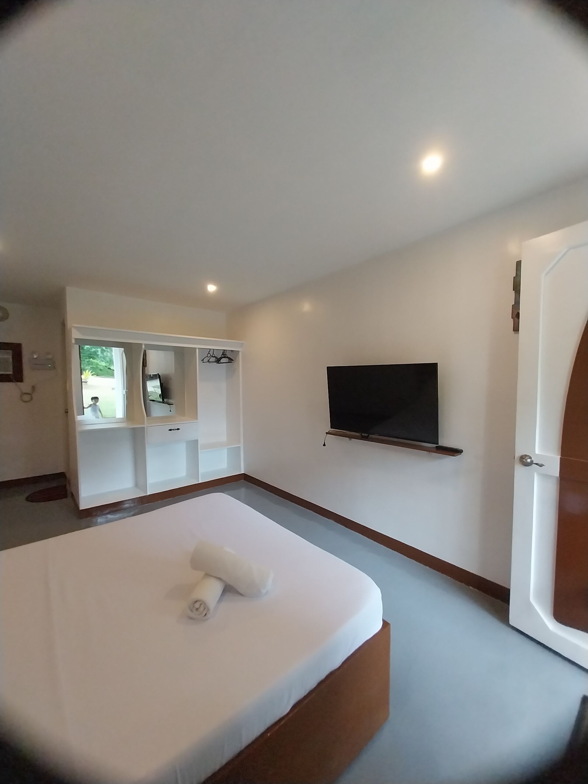 A modern hotel room with a large bed, a TV mounted on the wall, and a built-in wardrobe.