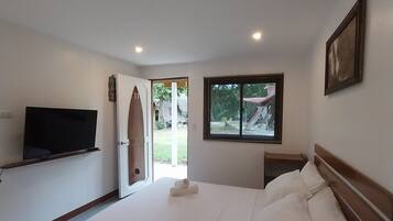 Un dormitorio con cama, televisión, ventana y puerta que da al exterior.