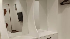 Un armario blanco con espejo, barra para colgar ropa y un cajón con asa.