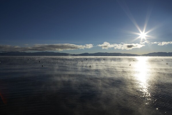 A calm body of water with a clear sky and distant mountains.