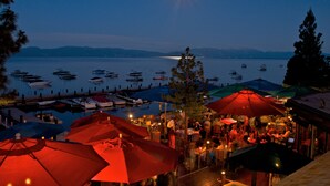 A waterfront restaurant with outdoor seating, boats docked in the background, and a clear view of the lake. - Sunnyside Restaurant & Lodge (Tahoe City)