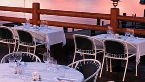 A waterfront restaurant with tables and chairs set for dining, overlooking a calm lake and mountains. - Sunnyside Restaurant & Lodge (Tahoe City)