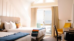 A hotel room with two beds, a desk, and a chair. The room has a large window with curtains and a view of the outdoors. - Sunnyside Restaurant & Lodge (Tahoe City)